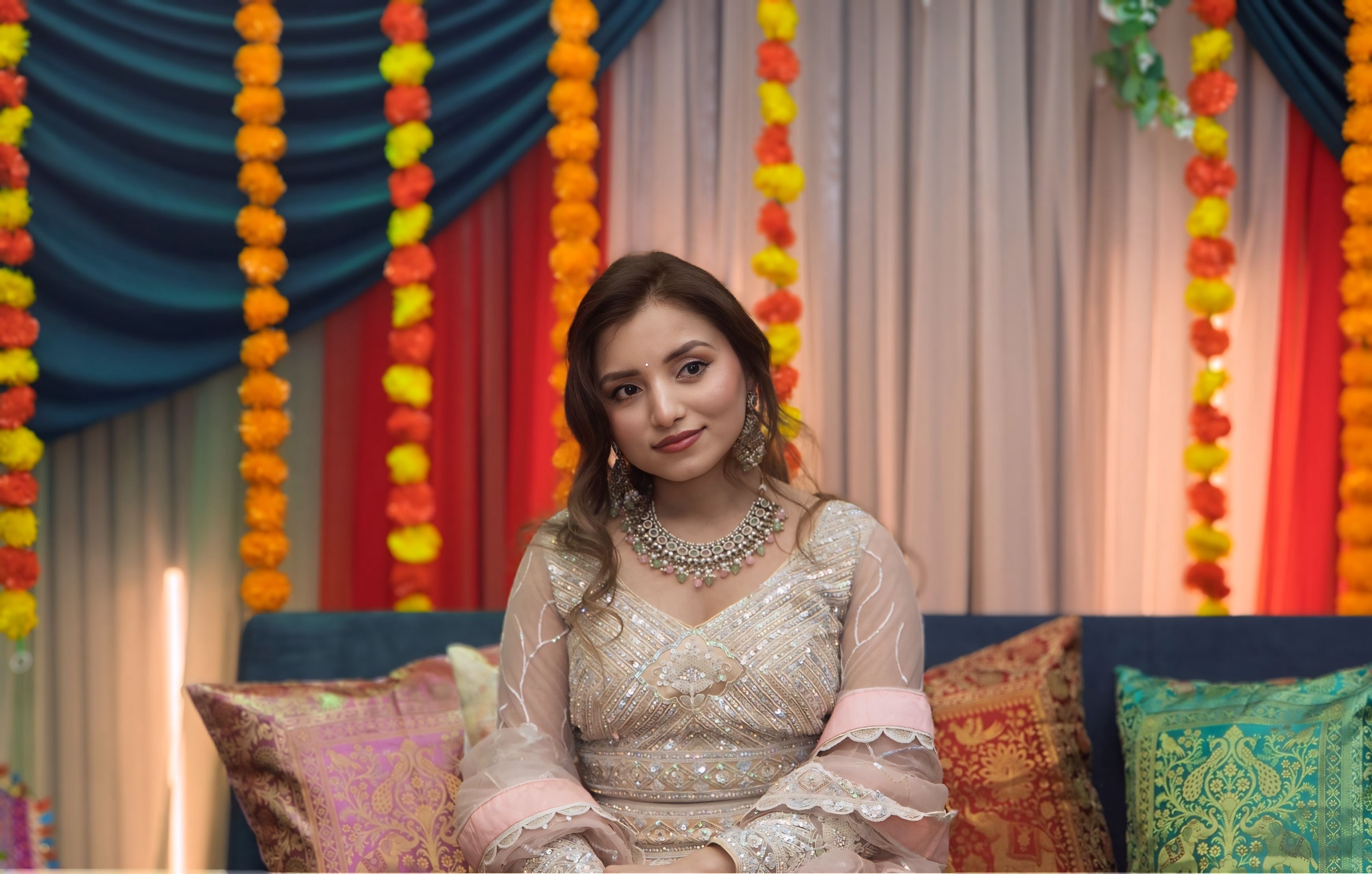 Bridal portrait — bride in embroidered lehenga with floral mehndi backdrop